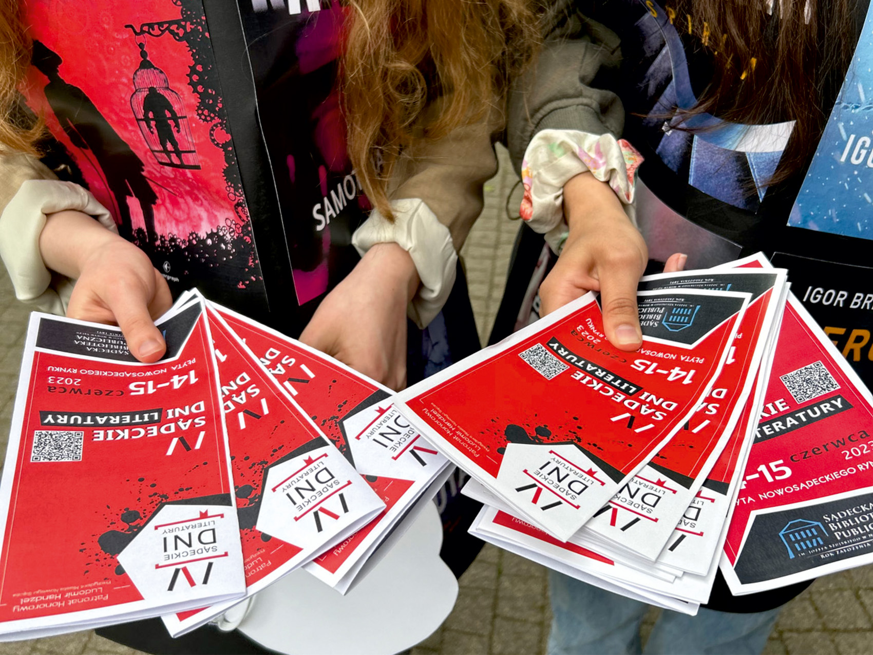 Happening Zbliżenie na ręce dwóch osób, które trzymają rozłożone w wachlarz ulotki.