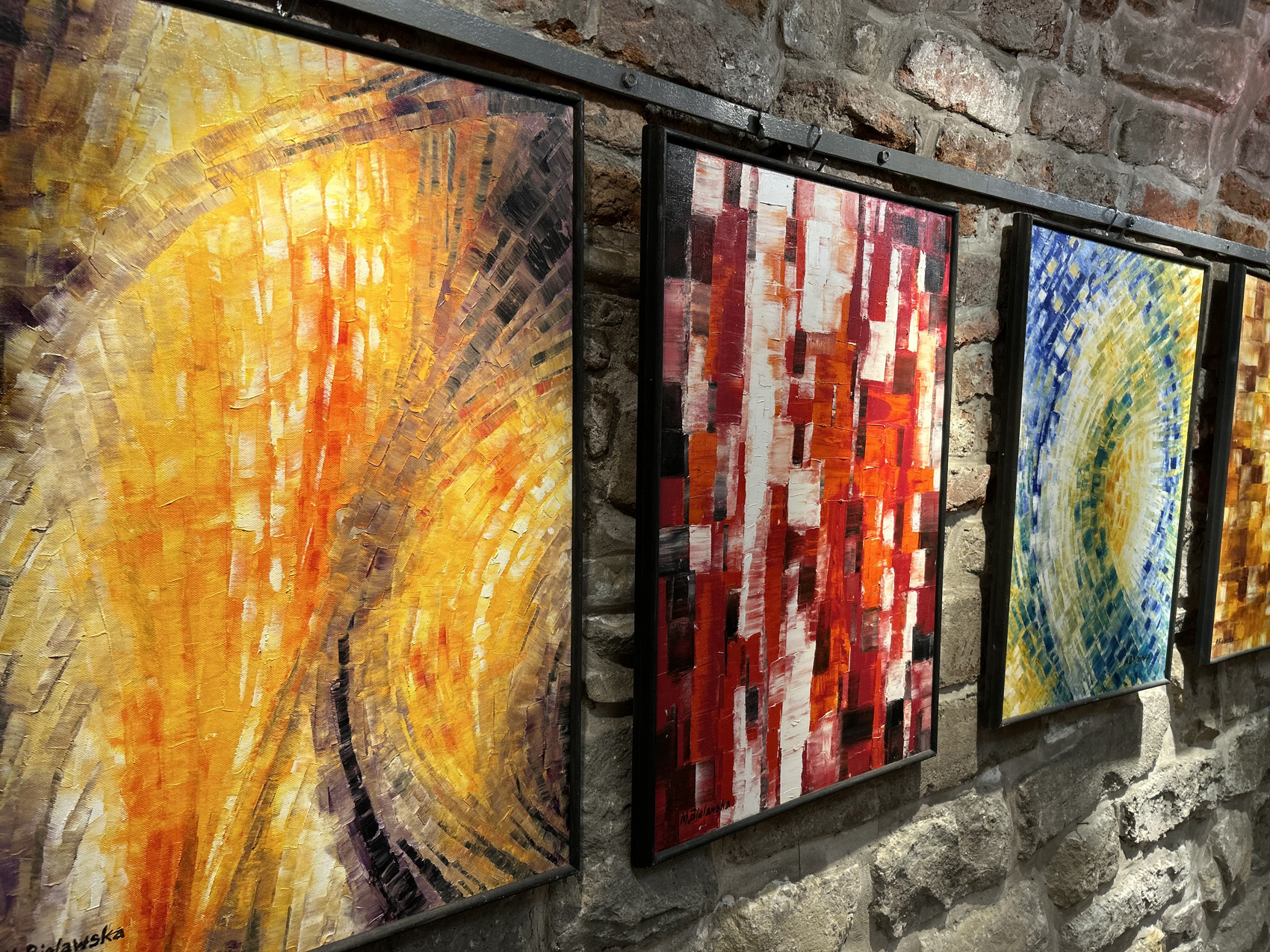 Na ścianie wiszą kolorowe obrazy.