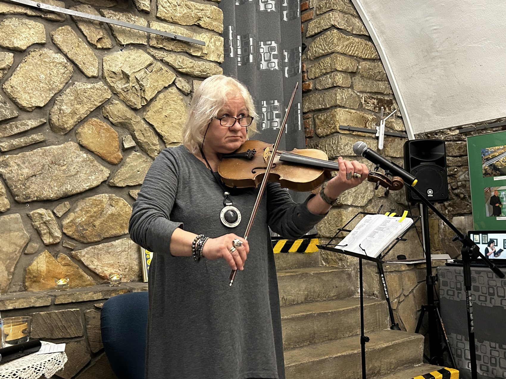 Wieczór wspomnień o Marii Piniańskiej (4) Kobieta gra na skrzypcach. Przed nią stoi mikrofon.