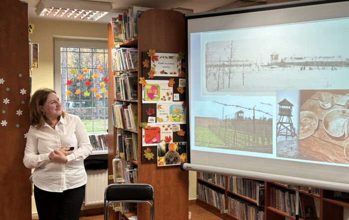 Kobieta trzyma w ręce pilot i patrzy na ekran projekcyjny.