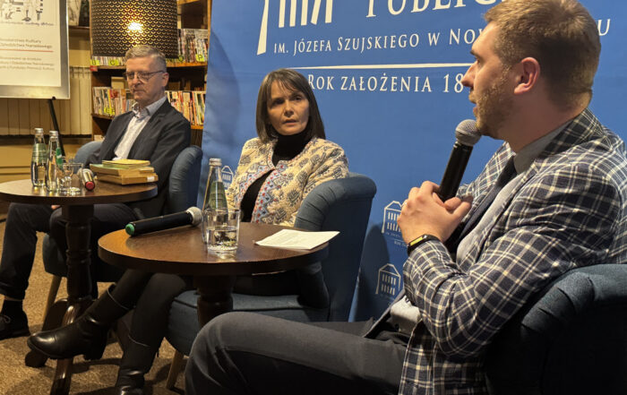 Trzy osoby siedzą przy stolikach i rozmawiają.