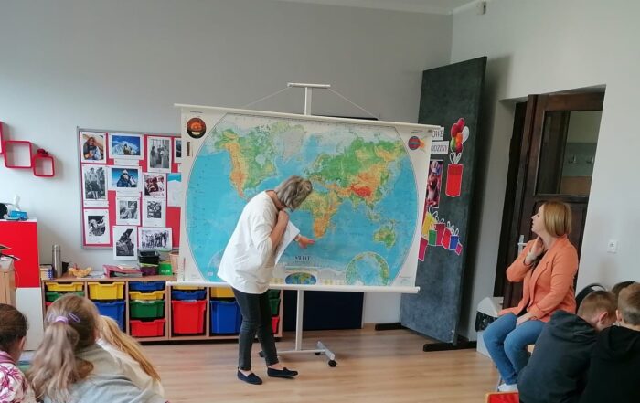Nauczycielka wskazuje punkt na mapie świata.