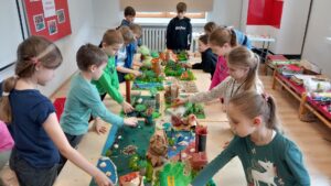 Dwanaścioro dzieci tworzy zielone makiety z papieru.